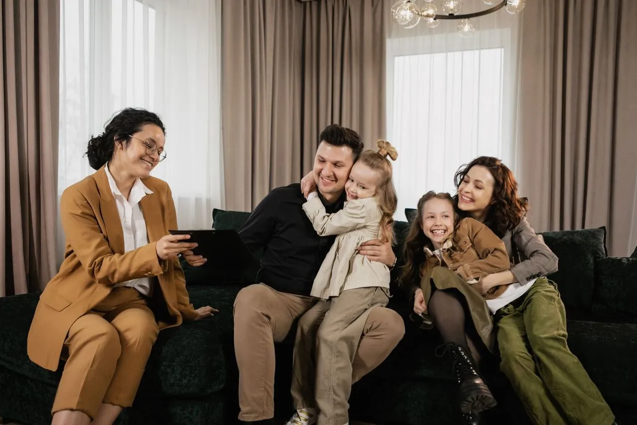 Une famille sereine vérifie son budget à table, protégée par une ombrelle symbolique.
